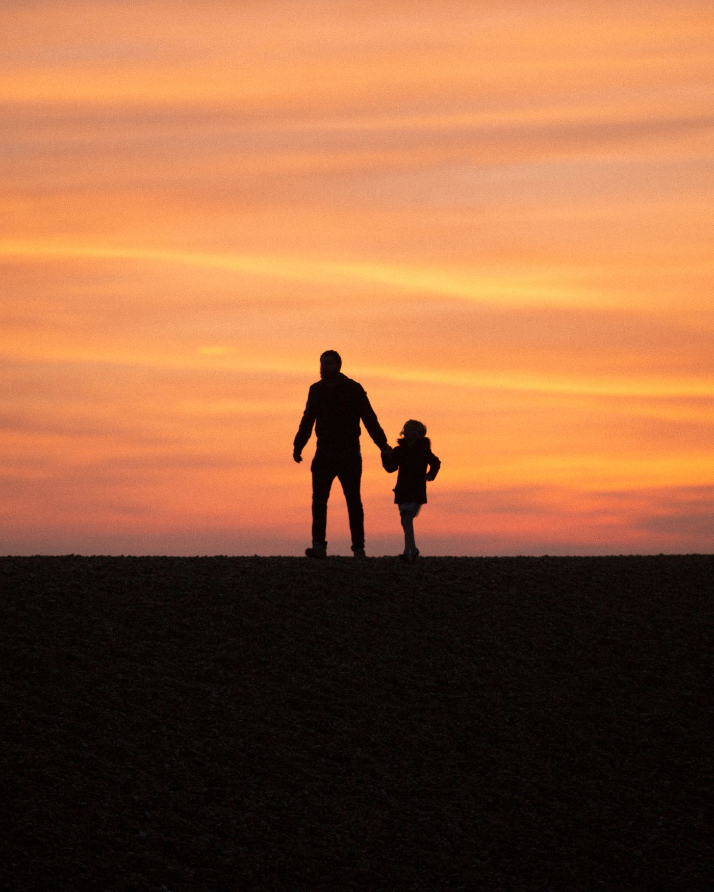 A parent and child walking together at sunset